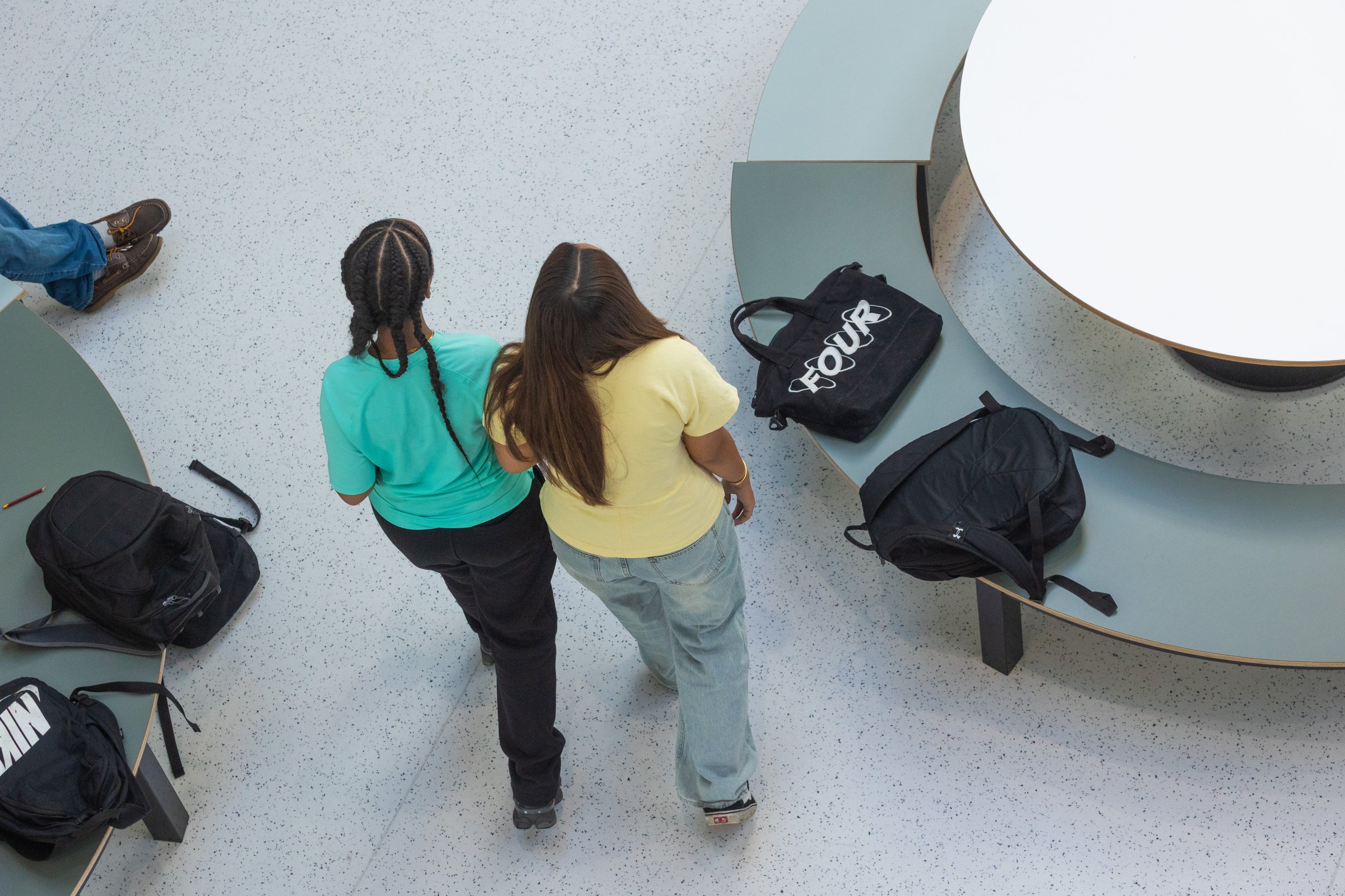 Twee leerlingen lopen samen door de aula, van bovenaf gezien
