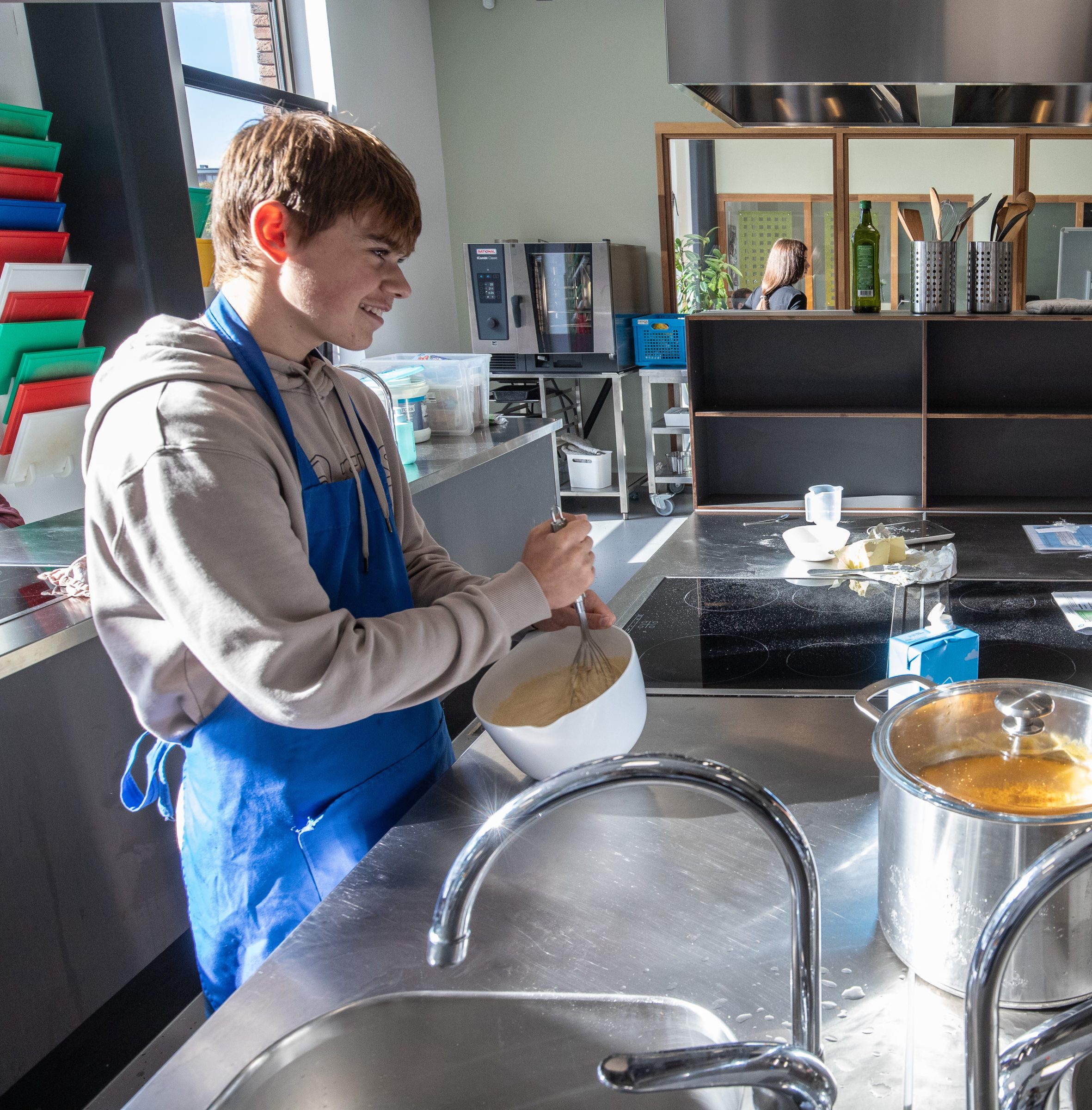 Leerling met schort klopt beslag in de schoolkeuken