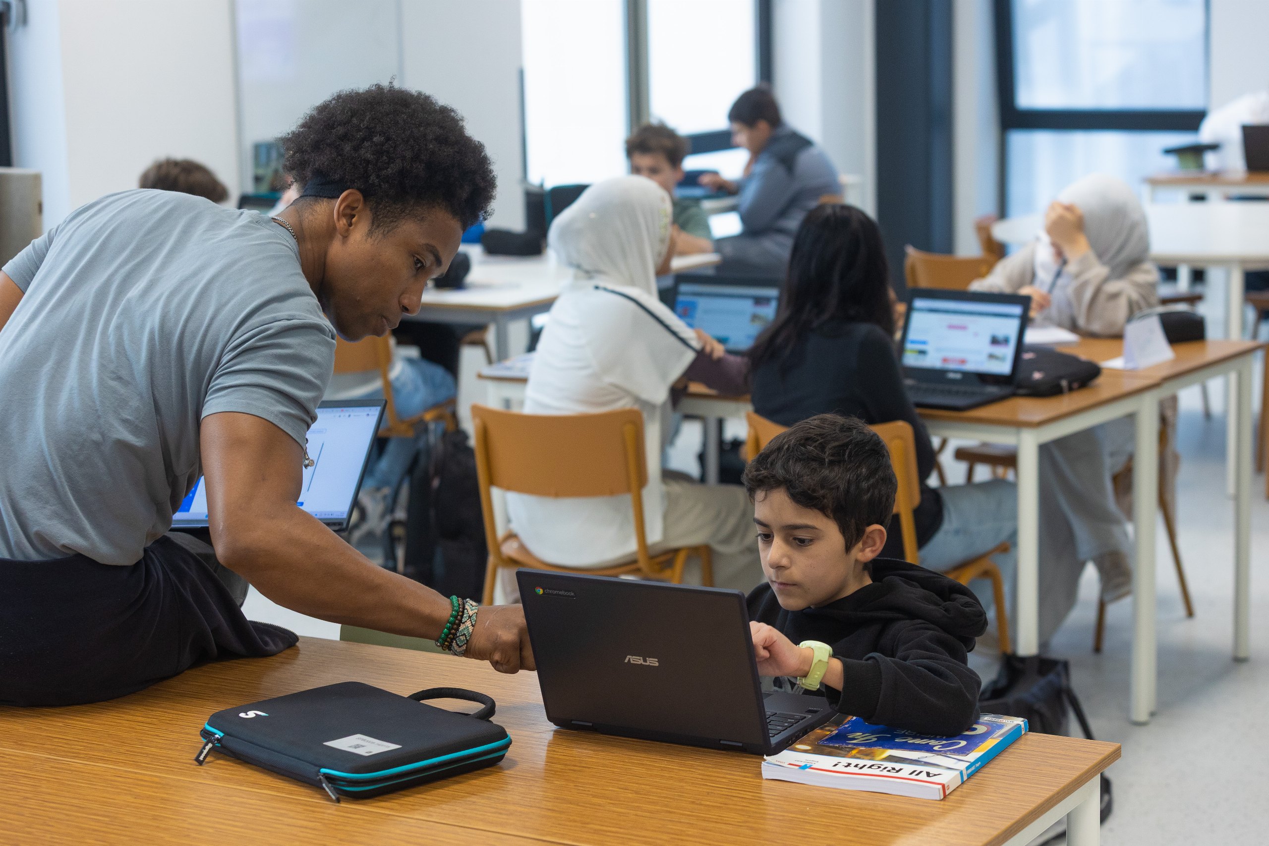 Docent helpt leerling met Chromebook