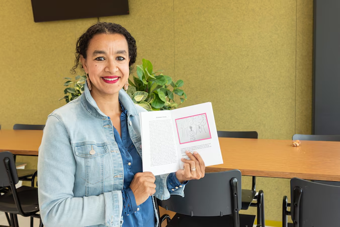 Docent Lelia Aarab houdt lachend een boekje met verhalen van leerlingen omhoog